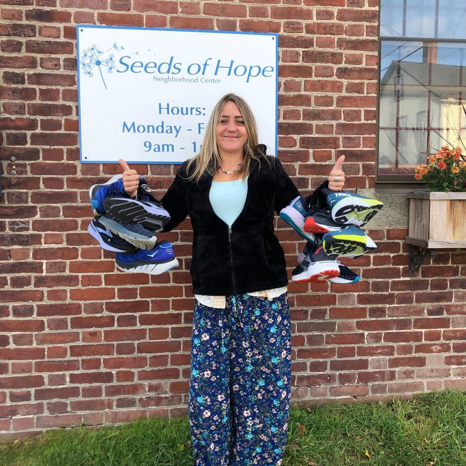 A volunteer posing while holding multiple pairs of shoes