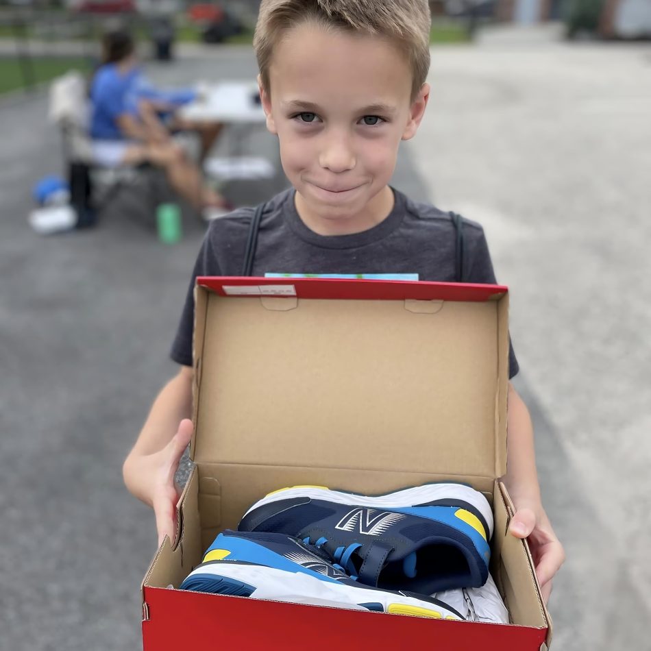 A young boy holding a box of new shoes