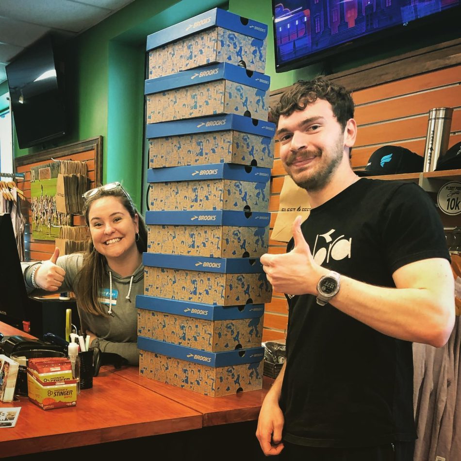 Two people posing next to a stack of shoe boxes